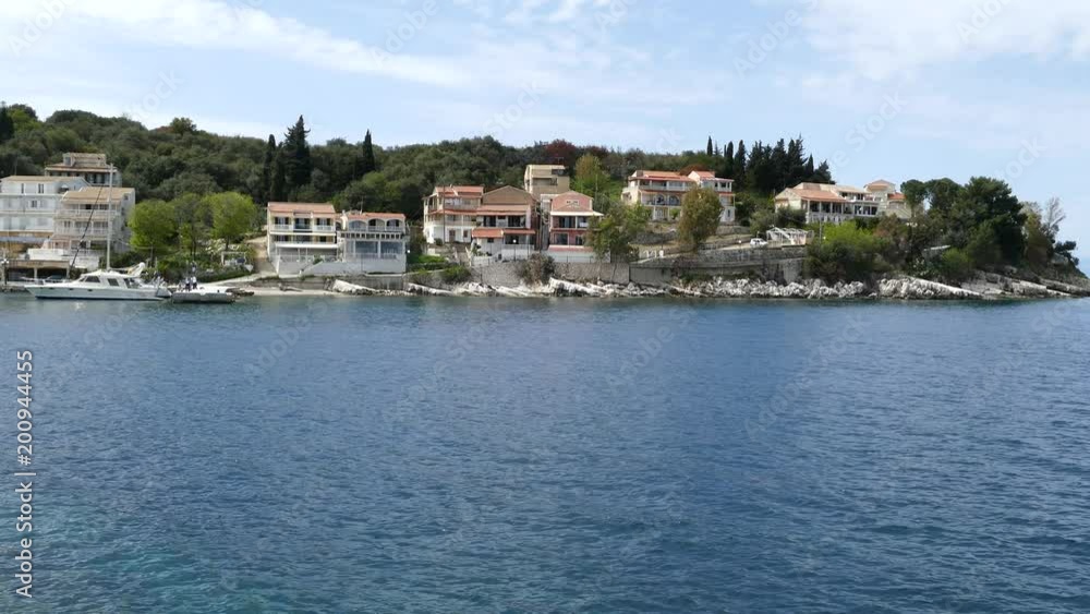 The Village of Kassiopi, Corfu Island, Greece. Rocky coast of Ionian Sea and houses on the hill. The Village of Kassiopi, Corfu Island, Greece. Rocky coast of Ionian Sea and houses on the hill.