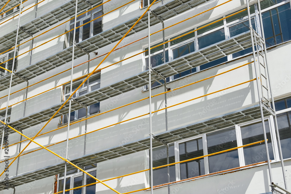 scaffolding near a new house, building exterior, construction and repair industry, white wall and window, yellow pipe