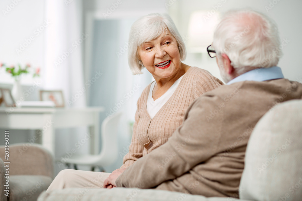 Pleasant communication. Cheerful nice aged woman looking at her husband while talking to him Pleasant communication. Cheerful nice aged woman looking at her husband while talking to him