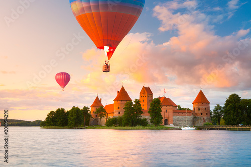 Landscape with red brick castle on island and flying air balloon in Trakai, Lithuania