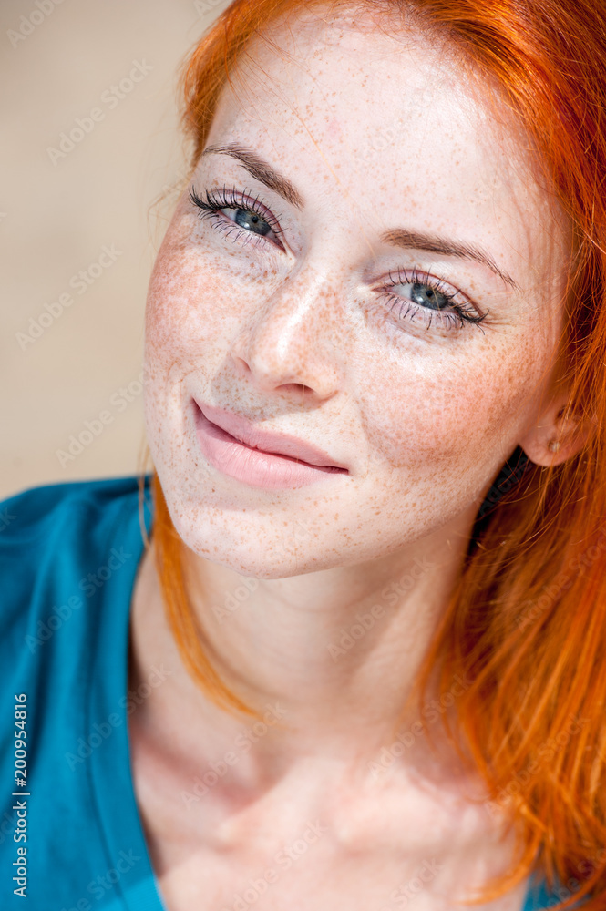 Closeup outdoor portrait of a young beautiful freckled redhead woman smiling dreamy Closeup outdoor portrait of a young beautiful freckled redhead woman smiling dreamy