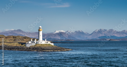 View on the old Eilean Musdile lighthouse in Scotland, with snowcapped highland peaks in the background photo