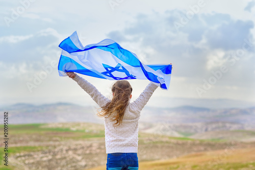 Little patriot jewish girl standing  and enjoying with the flag of Israel on blue sky background.Memorial day-Yom Hazikaron, Patriotic holiday Independence day Israel - Yom Ha'atzmaut concept photo