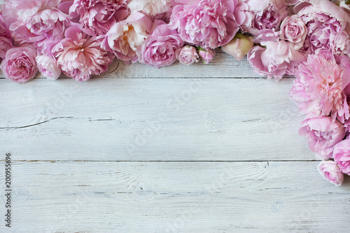 Pink peonies and roses on a wooden background