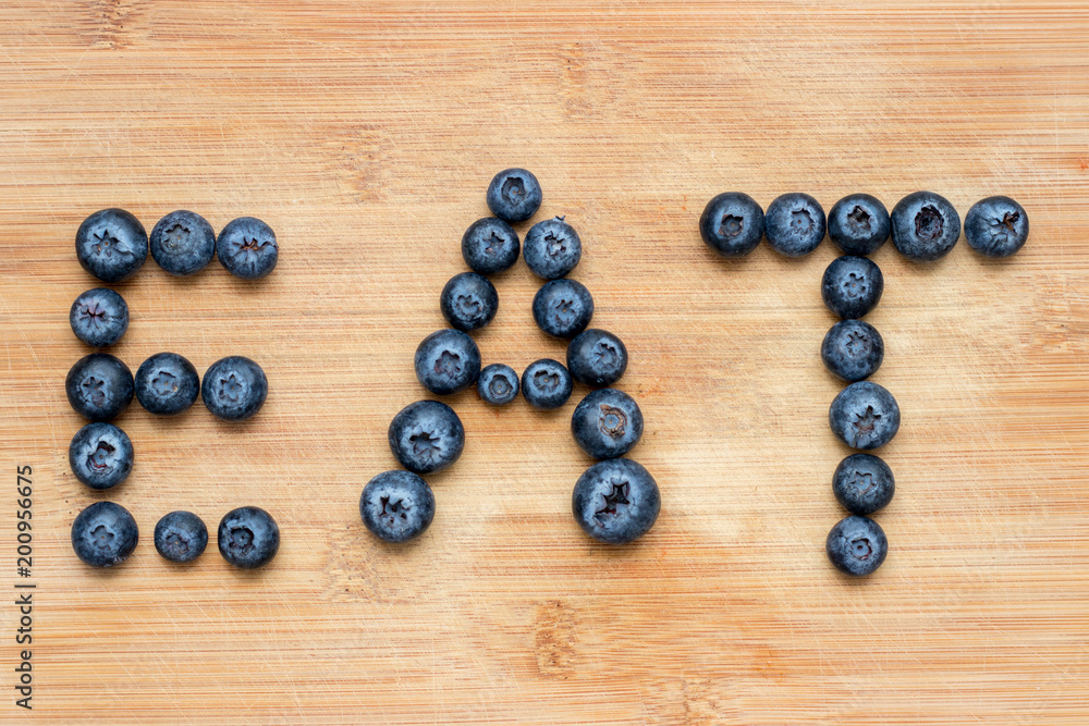 Word eat formed with blueberries on wooden background. Concept of healthy food. Word eat formed with blueberries on wooden background. Concept of healthy food.