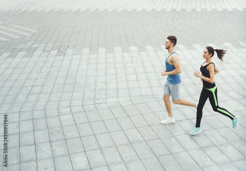 Young woman and man running in city copy space