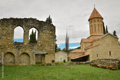 Fotografie Ancient historic church and brick wall on green grass in Georgia in sunny day