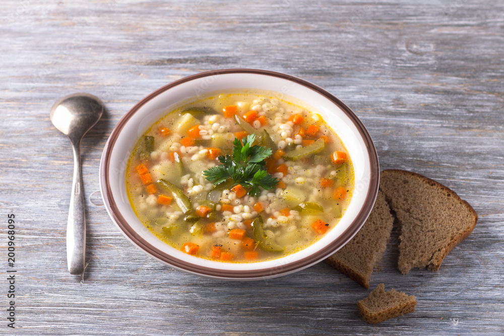 Vegan soup with pickled cucumbers and pearl barley, rassolnik. traditional homemade Russian cuisine. on a wooden table Vegan soup with pickled cucumbers and pearl barley, rassolnik. traditional homemade Russian cuisine. on a wooden table