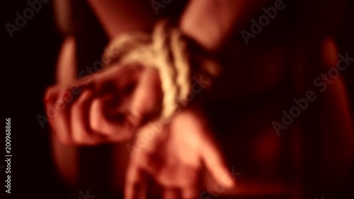girl has hands bound behind their backs with rope