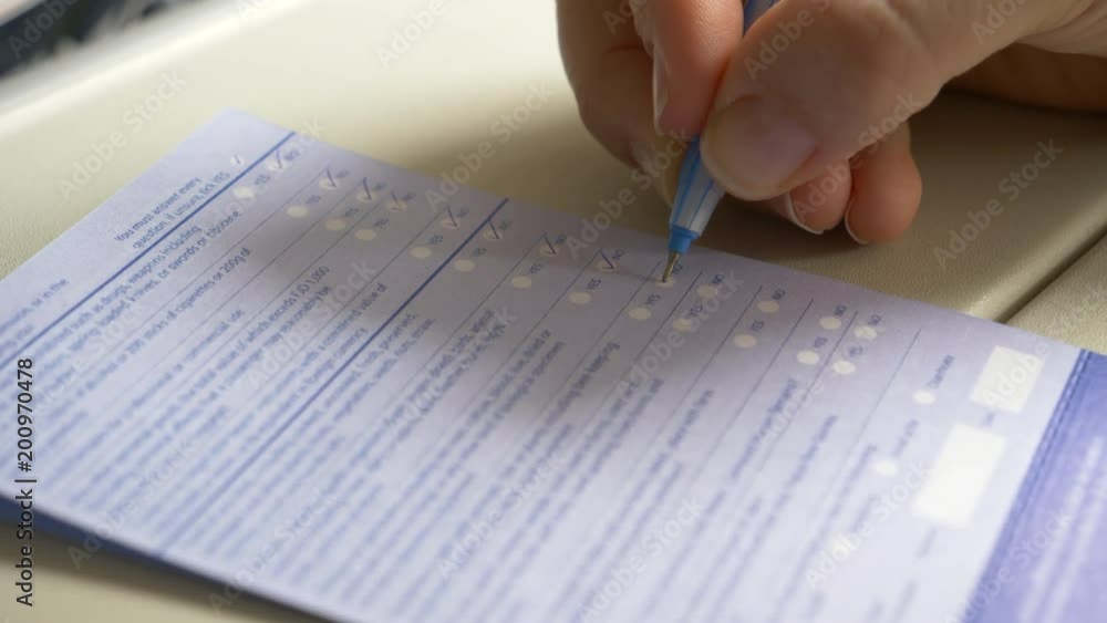 CLOSE UP: Female tourist ticking “no” to multiple questions on important immigration form while she flies to the United States. Businesswoman filling out paperwork for the airport customs office. CLOSE UP: Female tourist ticking “no” to multiple questions on important immigration form while she flies to the United States. Businesswoman filling out paperwork for the airport customs office.