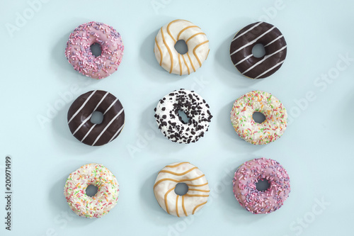 Sweet and colourful donuts glazed with sprinkles. Set of different type of donuts on the blue background.