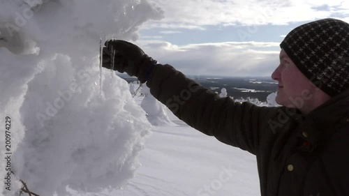 Man touching ice sticks, Male reaching for ice, in a snow covered forest, at a fjeld tunturi, in Riisitunturi national park, Lapland, Finland