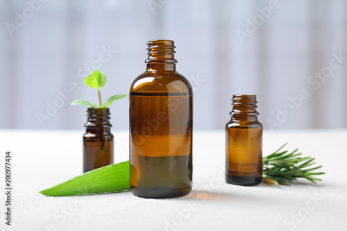 Bottles with essential oils and fresh herbs on table