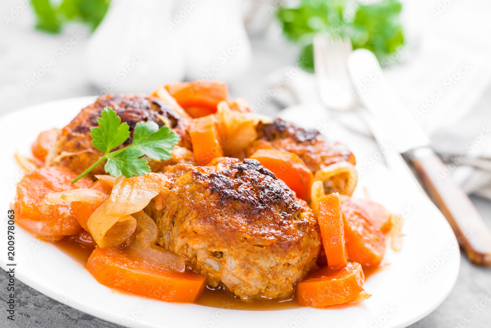 Fish meatballs or noisettes baked with carrot, onion and tomato sauce. Fish meatballs on plate Fish meatballs or noisettes baked with carrot, onion and tomato sauce. Fish meatballs on plate