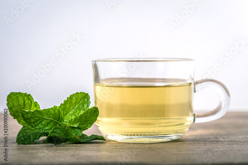 Close up a glass cup of mint tea with green fresh peppermint leaves , relaxation and healthy drink