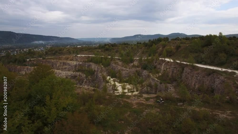 A young man on a moto bike rides along the cliff of the canyon. Aerial view 4k A young man on a moto bike rides along the cliff of the canyon. Aerial view 4k