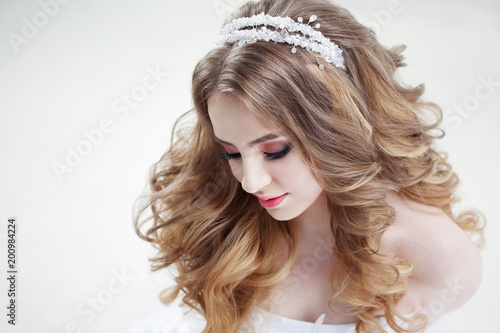 Young beautiful bride with luxurious curls. Wedding hairstyle with tiara.