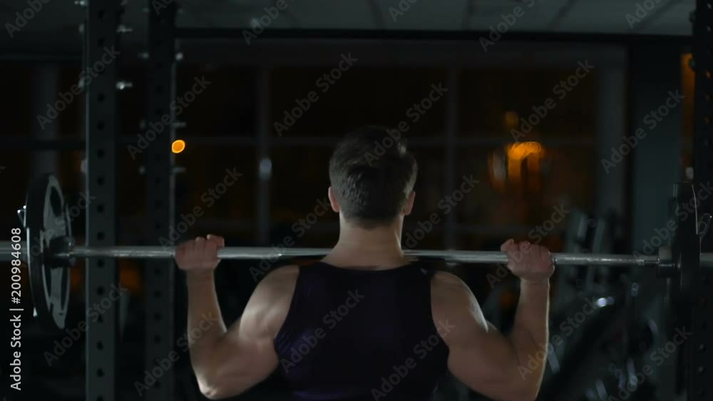 Bodybuilder lifting heavy barbell weights in gym at night, sport and fitness Bodybuilder lifting heavy barbell weights in gym at night, sport and fitness
