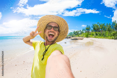 Handsome man having fun taking a selfie at the beach on holiday photo