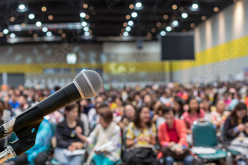 Microphone over the Abstract blurred photo of conference hall or seminar room in Exhibition Center background with Speakers on the stage and attendee background, Business meeting and education concept photo