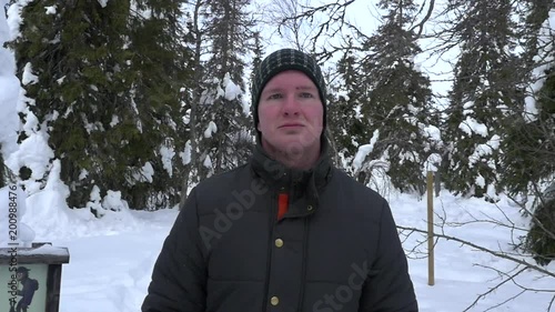 Man hiking in snowy forest, following a male walking in asnow covered pine tree forest, in a winter wonderland on a fjeld mountain fell, in Riisitunturi national park, Lapland, Finland photo