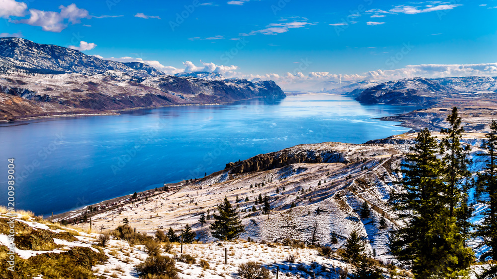 Naklejka premium Snow Covered Mountains surrounding Kamloops Lake in central British Columbia, Canada on a cold and crisp Winter Day under a blue sky