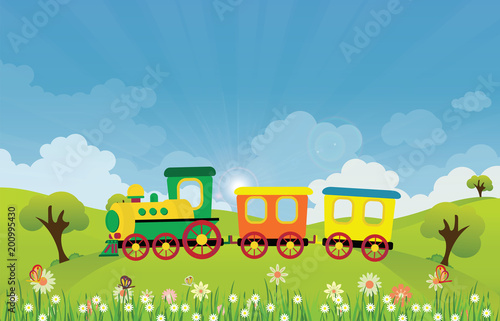 Toy train riding on Spring summer meadow landscape with sun rays and flowers.