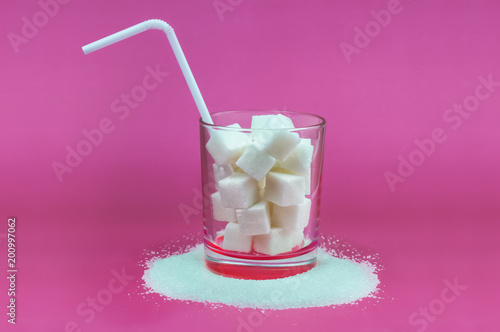 Obraz na plátne cubes of sugar in a glass with a drinking straw on bright pink background concep