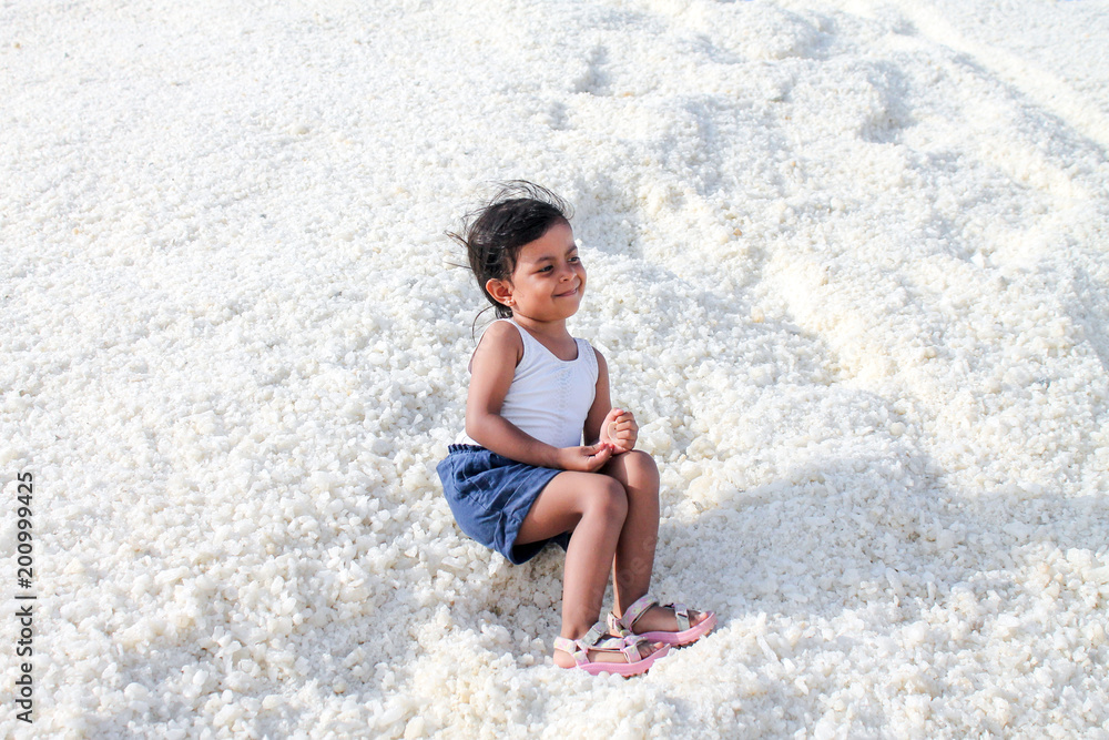 Little girl sitting on mountain of salt
