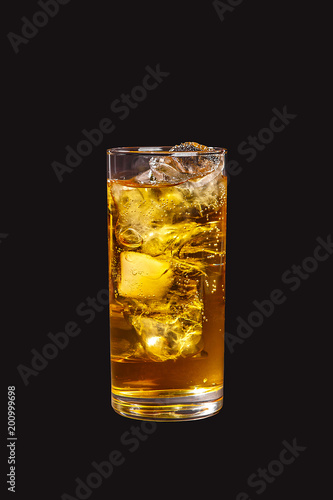 Single-color transparent cocktail, yellow refreshing carbonated in a high glass with ice cubes with apple, lemon, pear taste. Side view. Isolated black background. Drink for the menu