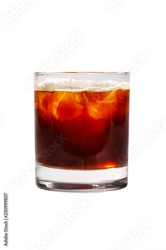 Single-colored transparent cocktail, brown, red refreshing carbonated with foam in a low glass with ice cubes and cola taste. Side view. Isolated white background. Drink for the menu