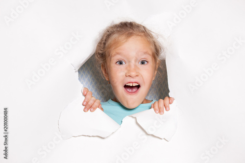 Surprised child looking out of a hole in paper