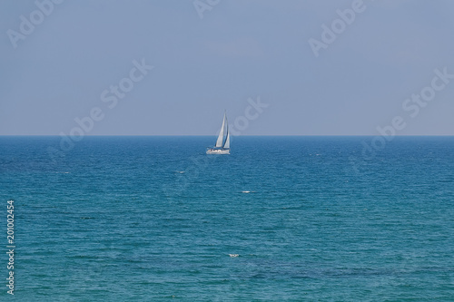 White sailboat floating on a calm sea. © zhdanovdi