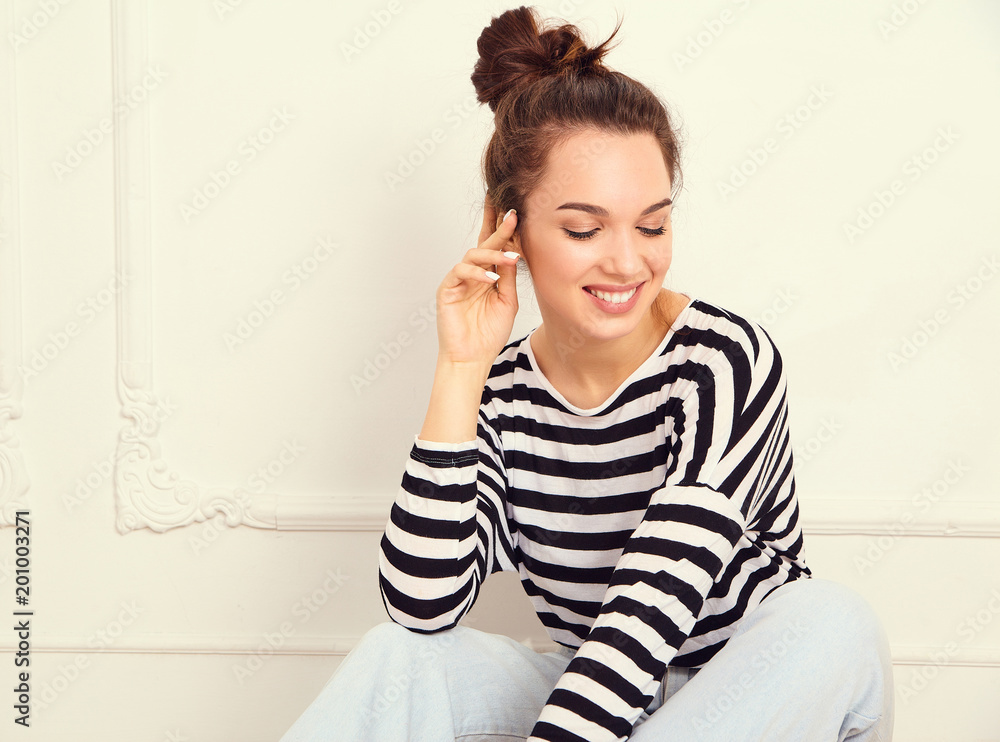 Portrait of young beautiful brunette woman girl model with nude makeup in summer hipster clothes posing near wall. Sitting on the floor Portrait of young beautiful brunette woman girl model with nude makeup in summer hipster clothes posing near wall. Sitting on the floor