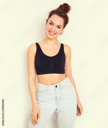 Portrait of young beautiful brunette woman girl model with nude makeup in summer T-shirt top and jeans hipster clothes posing near wall. Going crazy
