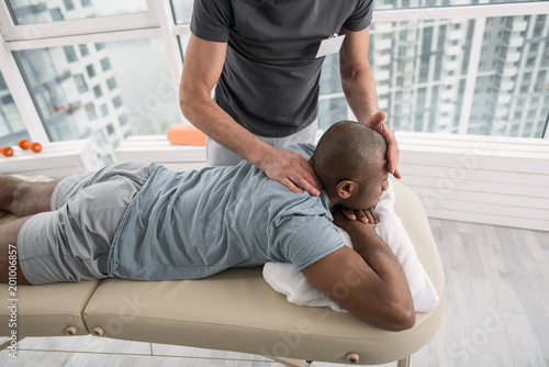 Medical center. Handsome young man lying on the medical couch while having a massage therapy