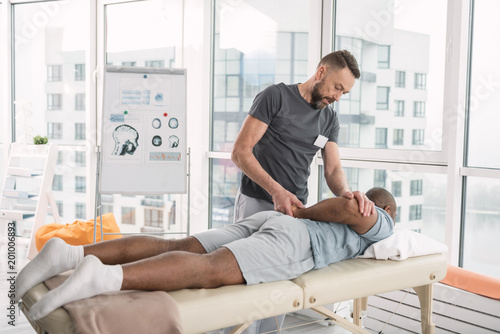 Professional therapy. Smart professional therapist using a special technique while doing massage for his patient