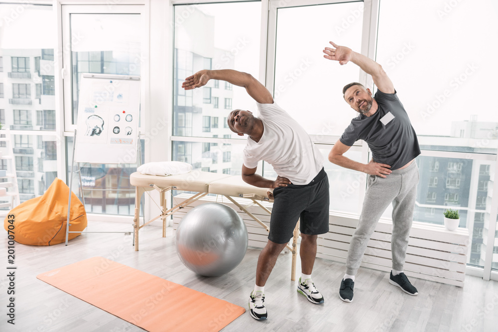 Sport is life. Pleasant nice men exercising while doing rehabilitation therapy Sport is life. Pleasant nice men exercising while doing rehabilitation therapy