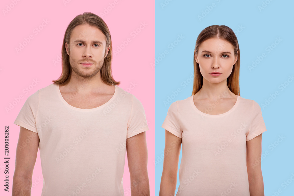 Confident looks. The portraits of a handsome young man posing on a pink background and a pretty woman next to him standing against a blue background Confident looks. The portraits of a handsome young man posing on a pink background and a pretty woman next to him standing against a blue background