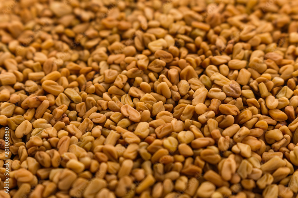 fragrant grains of fenugreek on a rustic background fragrant grains of fenugreek on a rustic background