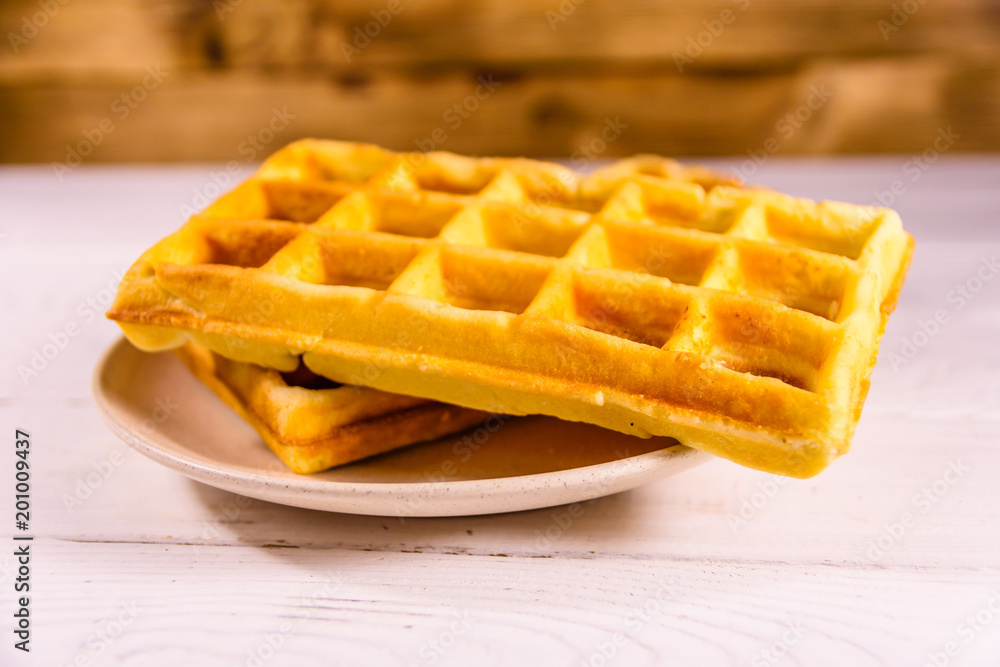 Ceramic plate with belgian waffles on wooden table Ceramic plate with belgian waffles on wooden table