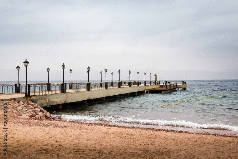 Beach, sea and pier in the water on a cloudy summer day