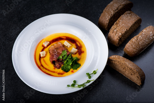 An appetizing pumpkin soup is served in a white plate in a restaurant photo