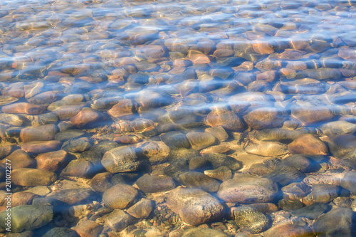 Crystal clear water of northern lake with stones on the bottom