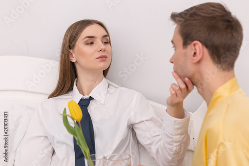 Submissive boy. Satisfied dominant woman wearing a tie and caressing her house husband