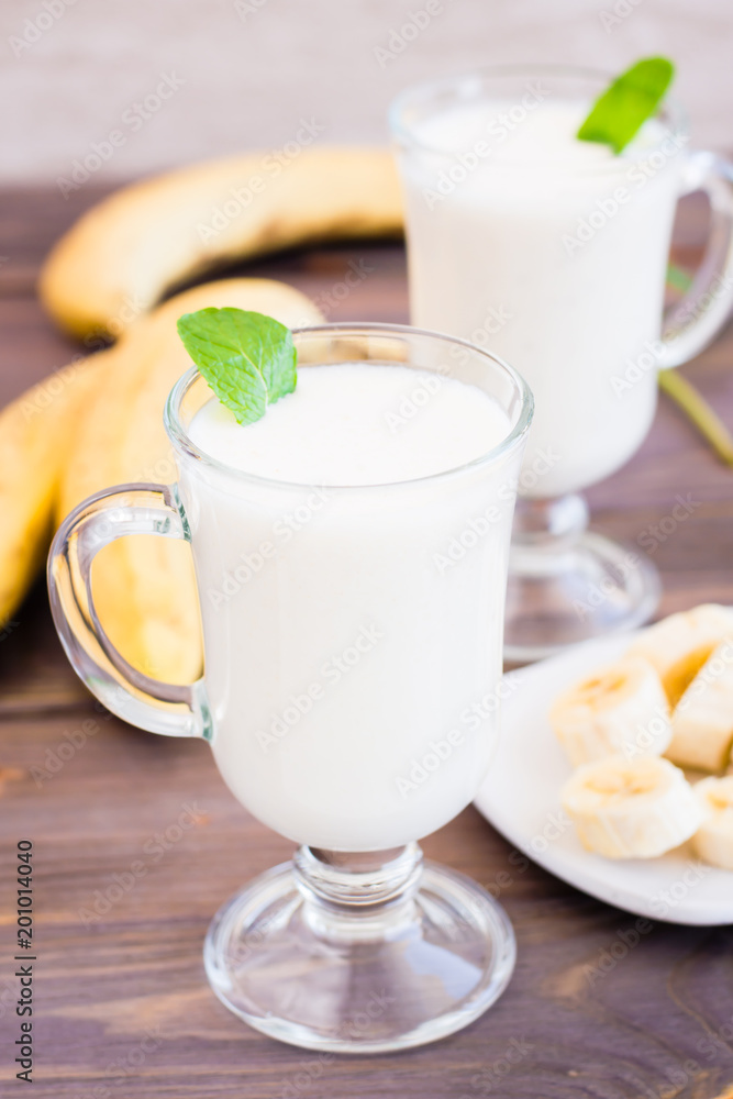 Banana smoothie with mint leaves in glasses on a wooden table Banana smoothie with mint leaves in glasses on a wooden table