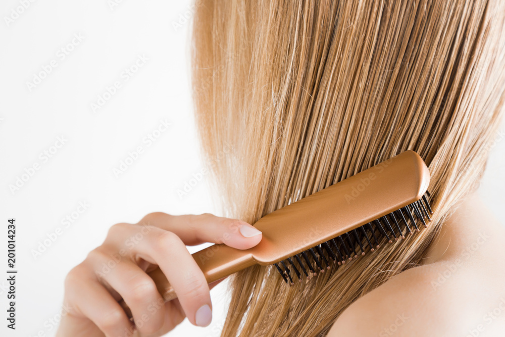 Young woman with comb brushing her wet, blonde, perfect hair after shower  on the white background. Care about beautiful, healthy and clean hair.  Beauty salon concept. Side view. Stock Photo | Adobe