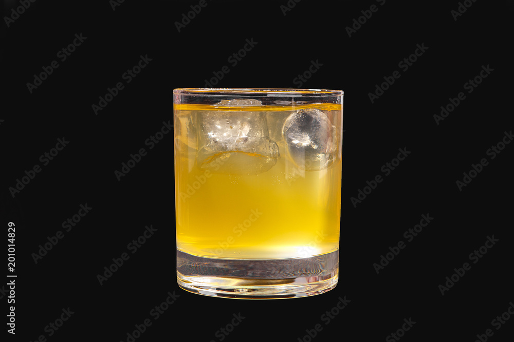 A single-colored transparent cocktail, refreshing in a low glass with radiant ice cubes, carbonated with a taste of melon, pineapple, pear, apple, fruit. Side view Isolated black background