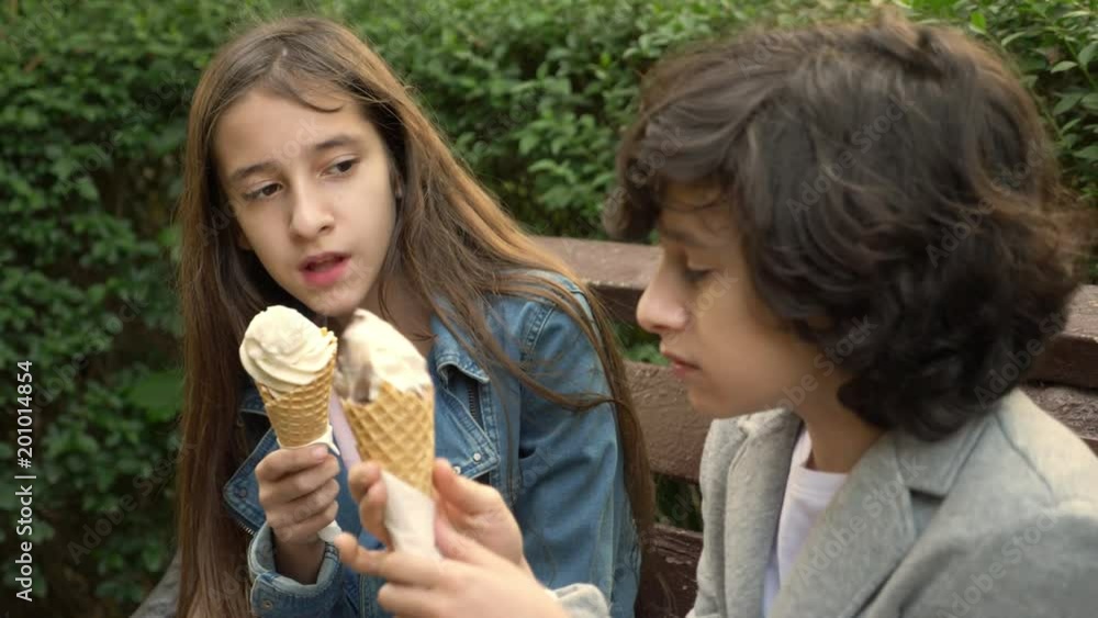 Vidéo Stock cute teenagers, boy and girl eating ice cream in the park ...