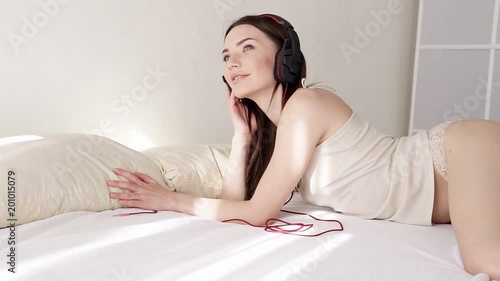 woman in lingerie lying in the bedroom listening to music from big headphone photo